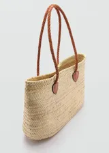 Bolso tipo tote de paja color beige con asas de cuero trenzado color marrón.