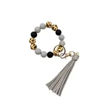 Llavero tipo pulsera con cuentas de silicona en tonos gris, negro y animal print, con colgante de flecos en cuero sintético gris claro.