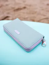 Billetera de poliuretano texturizado color rosado con cierre perimetral y logo metálico al frente.