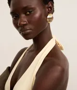 Aretes tipo botón redondos de bisutería, color dorado claro, con textura de líneas verticales acanaladas.