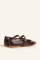 Zapato tipo Mary Jane color borgoña, de charol con correa sobre el empeine y hebilla redonda.