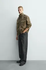 Cazadora relaxed fit de piel con acabado ante color verde militar. Tiene cuello subido, manga larga con puño abotonado, trabillas en los hombros, bolsillos de plastrón con solapa en el pecho y bolsillos de vivo en la cadera. El bajo es elástico y el cierre frontal es de cremallera oculta con solapa y botones a presión.