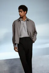 Pantalón negro de corte relajado, con cintura elástica ajustable con cordón, cierre con botón y corchete, bolsillos laterales y traseros.
