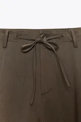 Pantalón cargo negro de corte amplio con cintura ajustable con cordón, bolsillos laterales y bolsillos tipo parche en las piernas.