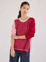 Suéter de lana con diseño color block en tonos rosa, rojo y beige.