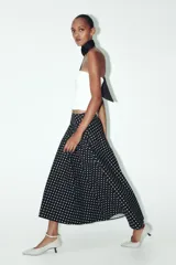 Falda midi negra con estampado de lunares blancos, de tiro alto y corte evasé.