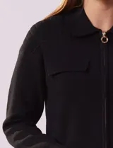 Cárdigan tejido negro con cuello con solapa y abertura central con cierre. Delantera con bolsillos simulados.