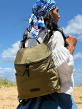 Mochila urbana de diseño compacto, color violeta/malva, con acabado ligeramente brillante. Presenta un compartimento principal con doble cierre superior y bolsillos laterales con cierre.