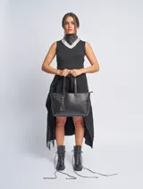 Cartera tote color marrón topo, de cuero sintético, con doble asa corta y cierre superior. Incluye un dije colgante con borla.