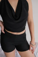 Conjunto de dos piezas (top y short) de lentejuelas color gris oscuro/plata. El top es estilo halter con escote drapeado y el short es tiro alto y ajustado.