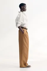 Pantalón de vestir color camel, de corte amplio, tiro alto y largo hasta el tobillo.