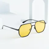 Lentes de sol con marco geométrico negro y lentes amarillos con protección UV400.