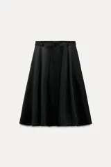 Falda midi negra de gabardina, tiro medio, cintura con trabillas, corte evasé con volumen y cierre frontal con cremallera y botón.