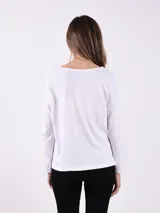 Remera blanca de manga larga con cuello redondo y estampado plateado con la frase "Stay Beautiful".