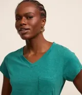 Blusa blanca de algodón con cuello en V, manga corta y bolsillo frontal.
