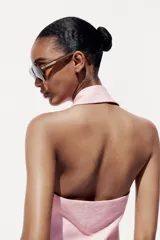 Chaleco rosa con cuello halter y escote pico con solapa. Espalda descubierta. Bolsillos delanteros con solapa. Cierre frontal cruzado con botones.