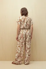 Pantalón ancho de tela liviana con estampado de hojas color crema sobre fondo azul. Tiene cintura elastizada con lazo ajustable.