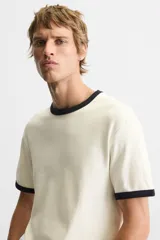 Camiseta azul marino de corte recto, con cuello redondo y mangas cortas. Presenta ribete blanco en cuello y mangas.