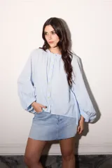 Camisa celeste super holgada con hombro caído y manga ancha. Tiene un volado en el cuello y efecto arrugado en la espalda.