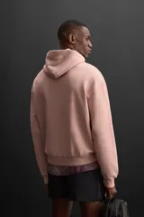 Sudadera con capucha color rosa viejo, confeccionada en tejido de algodón. Tiene cuello con capucha ajustable, manga larga, bolsillo tipo canguro y logo bordado en el pecho.