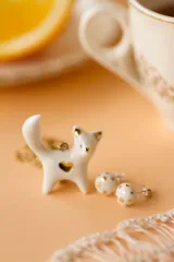 Par de aros tipo botón blancos con puntos dorados.