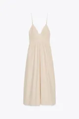 Vestido midi color crema de popelín, con escote en pico, tirantes finos ajustables, bolsillos laterales ocultos y detalle de pliegues. Incluye forro interior.