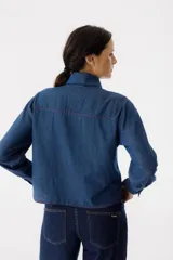 Camisa de jean azul con bordado de corazones rojos en el cuello y pespuntes rojos en los bordes.