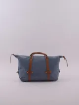 Bolso de viaje negro con detalles en cuero marrón, doble asa de mano y cierre superior con cremallera.