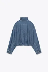 Chaqueta corta de denim azul con cuello alto, manga larga con hombros caídos, bolsillos laterales, bajo con elástico y cierre frontal con cremallera y botones ocultos.