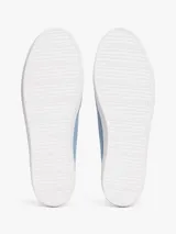 Zapatillas de lona de corte bajo, color celeste claro con efecto lavado, suela de goma blanca y cordones a tono. Presentan un pequeño logo esmaltado de Tommy Hilfiger en el lateral exterior.