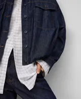 Campera bomber de denim de algodón color azul oscuro, con cuello solapa, manga larga con puño ancho, botonadura frontal, bolsillos con solapa y botón en el pecho, canesú en la espalda y bajo elástico redondeado.