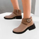 Bota corta de cuero color marrón con cierre lateral, suela de goma negra y hebilla decorativa.