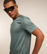 Remera deportiva gris con cuello redondo, mangas cortas, estampa heat print y detalle en los hombros. Confeccionada en tejido de malla con tecnología Dry.