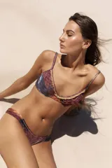 Conjunto de bikini con estampado batik en tonos azul, marrón y rosa. El corpiño es de aro con volados en el escote y tiras para atar. La bombacha es clásica con laterales fruncidos. Confeccionado en lycra con protección UV50 y proceso anticloro.