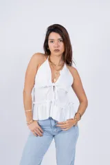 Top rosa con escote halter, volados en el cuello y en el ruedo, y lazo ajustable en el frente.