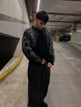 Sweater negro con cuello redondo y diseño geométrico en gris en la parte superior del pecho y hombros.