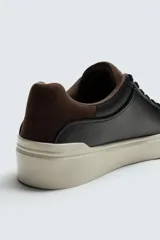 Zapatillas deportivas blancas de caña baja con detalle de color gris en el talón y suela con volumen.