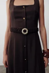 Vestido midi color marrón oscuro, sin mangas, con escote cuadrado, detalle de botones frontales y cinturón elástico con hebilla dorada.