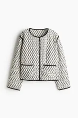 Campera corta acolchada de algodón con estampado floral en blanco y negro, cuello redondo, cierre frontal con botones a presión, bolsillos delanteros de parche y forro de algodón.