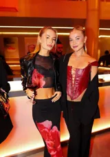 Conjunto de top y falda de malla transparente negra con estampado de flores rojas. El top es corto, sin mangas y con cuello redondo. La falda es larga y ajustada al cuerpo.