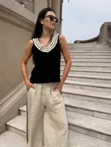 Top negro de cuero con escote en V y apliques de caracoles cosidos a mano en el escote.