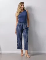Pantalón capri de algodón estampado a rayas verticales en tonos celeste, rosa y beige. Tiene pretina elastizada, bolsillos delanteros y tajos laterales con botones.