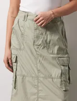 Falda larga color beige, de corte recto, con bolsillos cargo laterales y traseros, pretina con pasadores, botón y cierre.