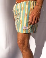 Short de baño de microfibra con estampado de rayas verticales en tonos celeste y beige, con motivos geométricos en color ocre. Tiene cintura elastizada marrón con cordón ajustable, dos bolsillos laterales y uno trasero.