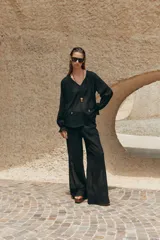 Pantalón negro de tiro alto con cintura elástica ajustable con cordones laterales, forro interior corto y pernera ancha.