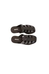 Sandalia plana negra de cuero vacuno con tiras entrelazadas y hebilla lateral metálica.