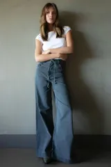 Pantalón de jean azul oscuro de pierna ancha con detalle de trenzado en bolsillos y cinturón.