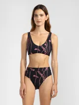 Bikini negro con estampado de cadenas y tigres en color rosa. El corpiño es de corte deportivo y la bombacha es de tiro alto.