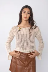 Top de tejido calado color marrón con mangas largas acampanadas y detalle de broches decorativos en el escote.