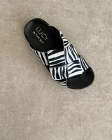 Sandalias bajas de cuero negro con tiras anchas cruzadas y plantilla anatómica color camel.